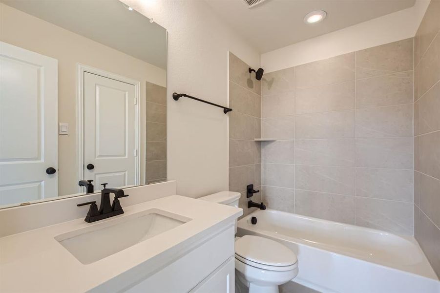 Full bathroom with vanity, tiled shower / bath combo, and toilet