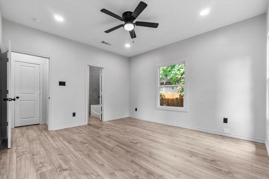 Unfurnished bedroom with ensuite bath, ceiling fan, and light wood-type flooring