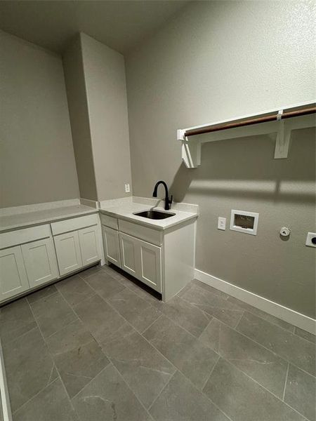 Laundry area featuring washer hookup, tile patterned flooring, electric dryer hookup, cabinets, and sink