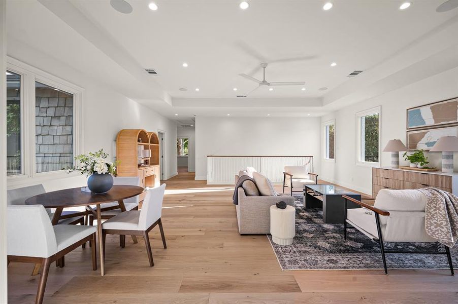 Living room featuring light wood-type flooring, a tray ceiling, and ceiling fan