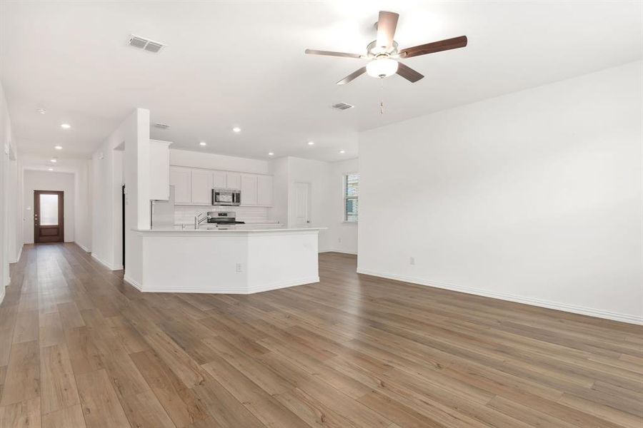 Unfurnished living room with ceiling fan, sink, and hardwood / wood-style flooring