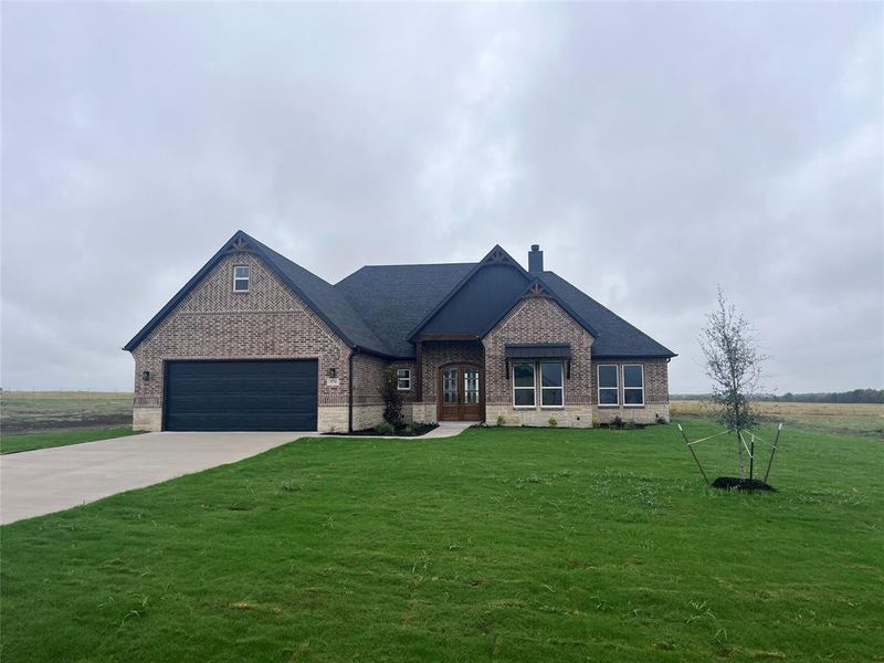 French country style house featuring a garage and a front lawn