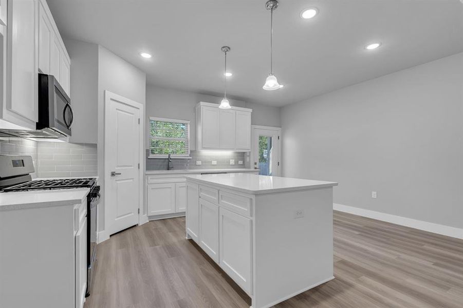 Kitchen featuring light hardwood / wood-style flooring, white cabinets, range with gas cooktop, and a kitchen island