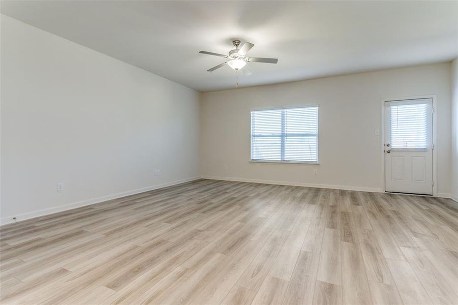 Unfurnished living room featuring ceiling fan, light wood-type flooring, and plenty of natural light