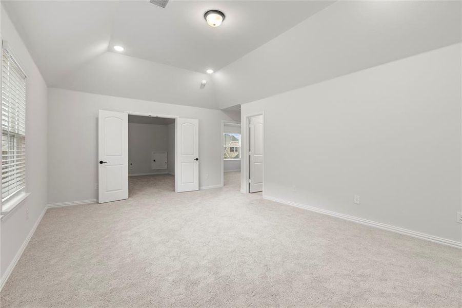 Unfurnished bedroom with lofted ceiling and light colored carpet