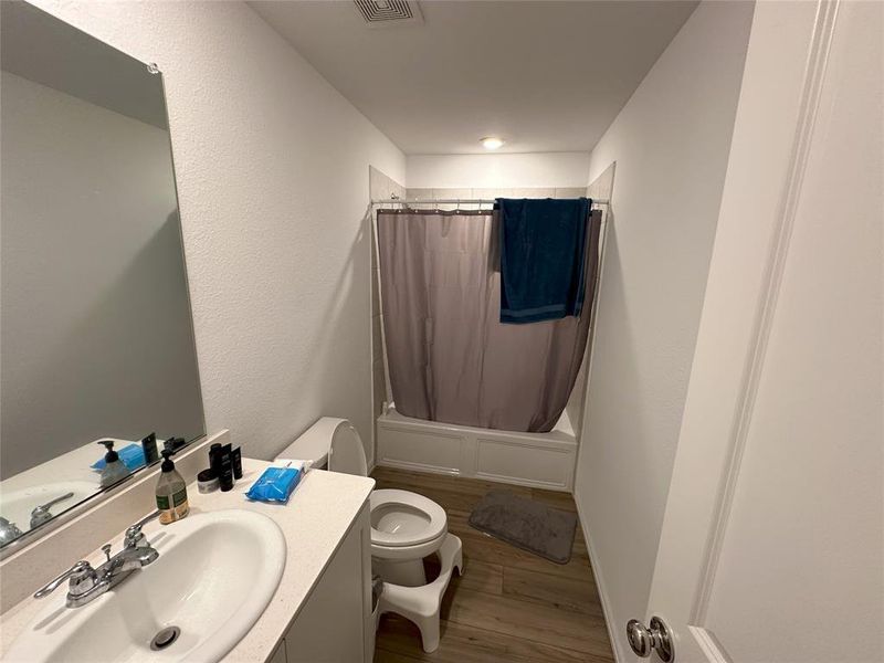 Full bathroom with vanity, toilet, hardwood / wood-style floors, and shower / bath combination with curtain