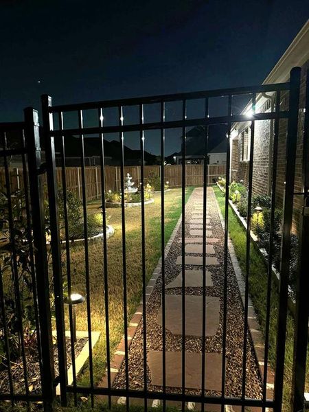 Gate at twilight featuring a lawn