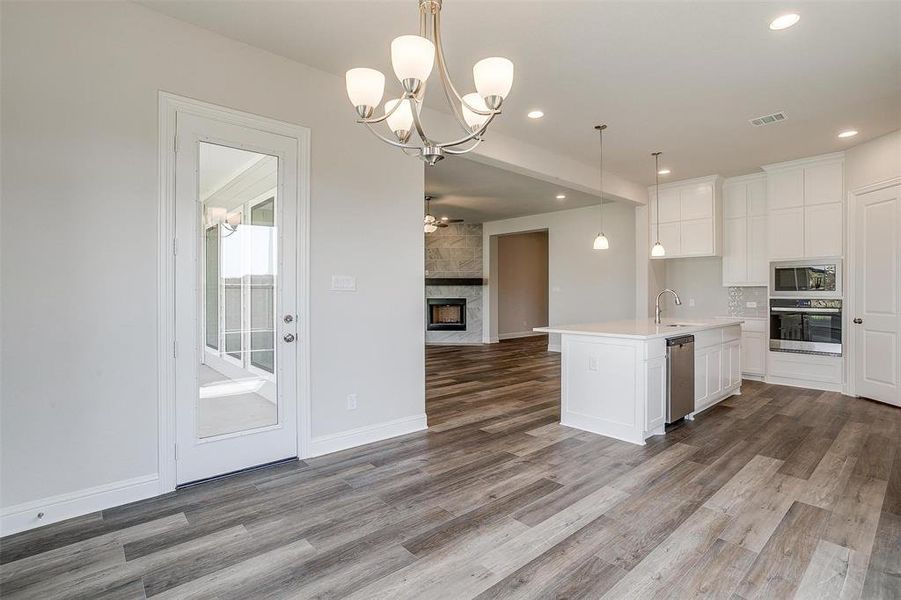 Kitchen featuring appliances with stainless steel finishes, sink, pendant lighting, a kitchen island with sink, and wood-type flooring