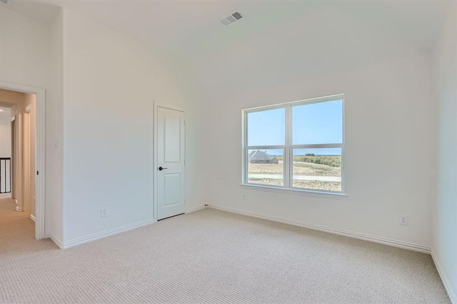 Carpeted empty room with high vaulted ceiling