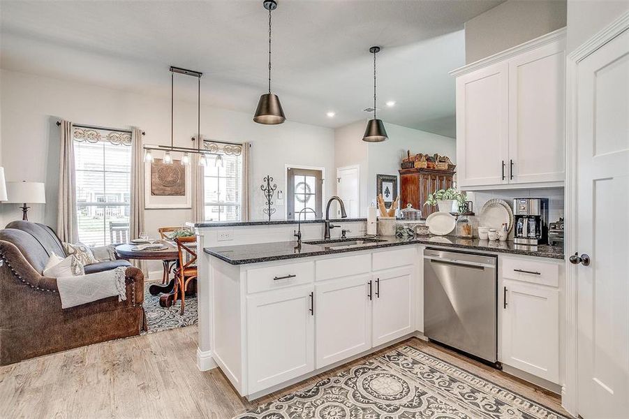 Kitchen featuring white cabinetry, pendant lighting, sink, dishwasher, and light hardwood / wood-style floors