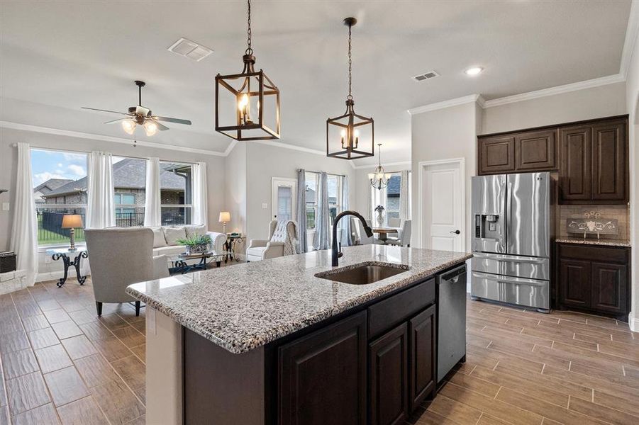 Kitchen featuring stainless steel appliances, pendant lighting, backsplash, sink, and a kitchen island with sink