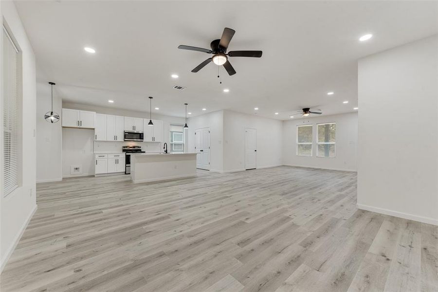 Unfurnished living room with light wood-type flooring, sink, and ceiling fan