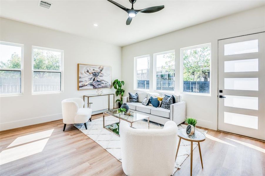 Living room featuring ceiling fan, a wealth of natural light, and light hardwood / wood-style floors