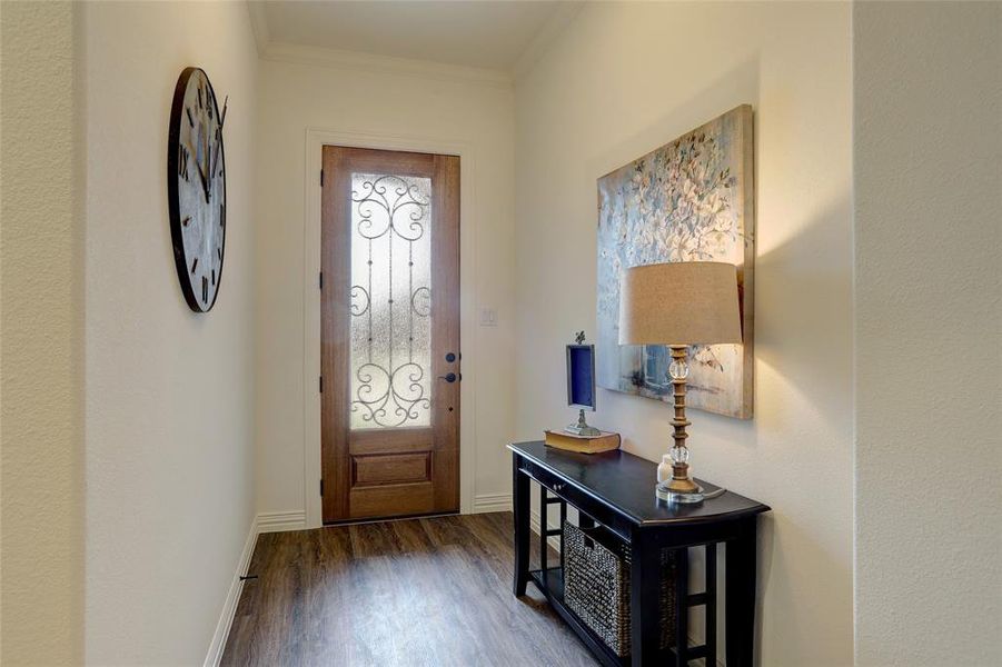 Entrance foyer with crown molding and dark wood-type flooring