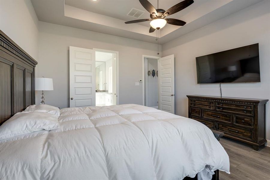 Bedroom featuring ceiling fan, a raised ceiling, and dark wood-type flooring