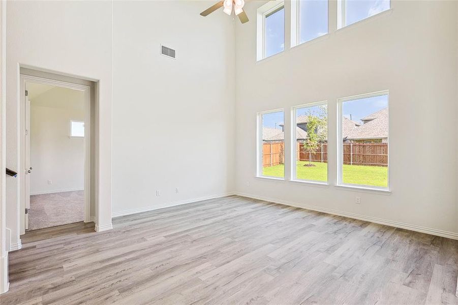 Empty room featuring light hardwood / wood-style floors, ceiling fan, and a towering ceiling