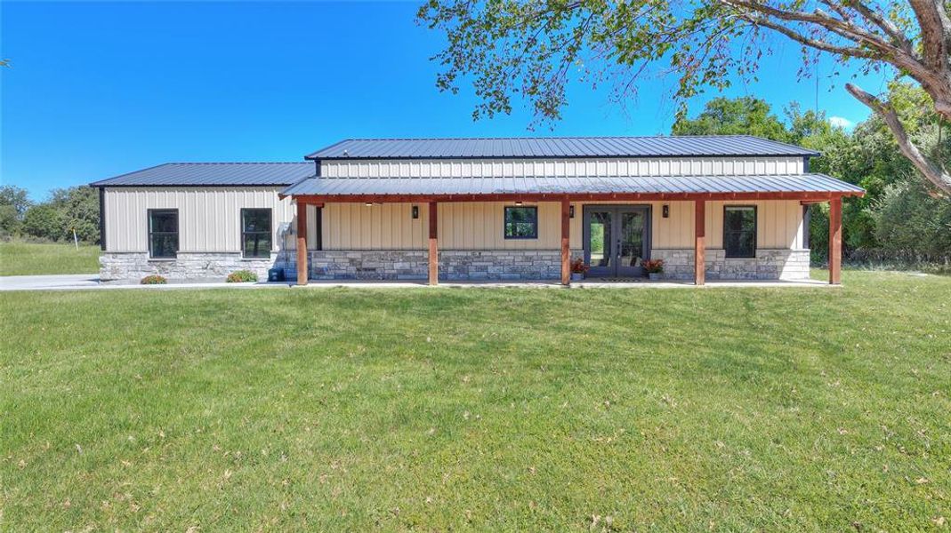 Rear view of property with a lawn and covered porch