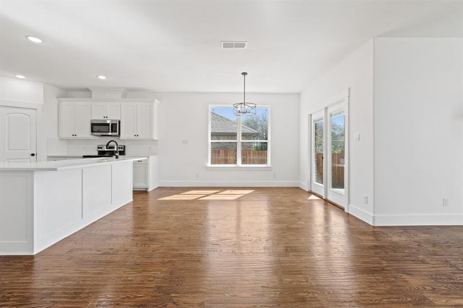 Kitchen with white cabinets, appliances with stainless steel finishes, dark hardwood / wood-style floors, and pendant lighting