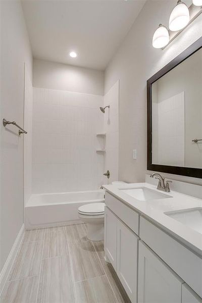 Full bathroom with tiled shower / bath, vanity, and toilet