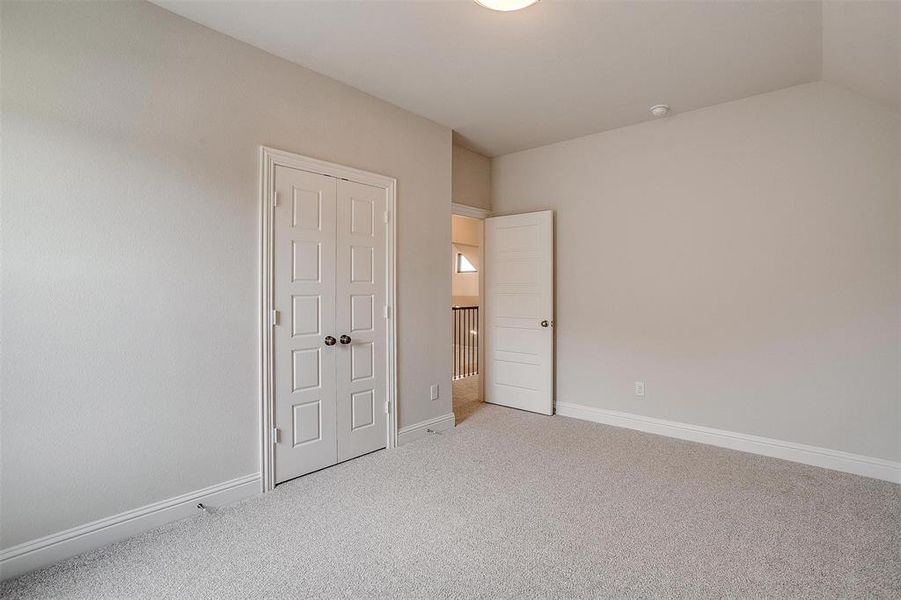 Unfurnished bedroom with carpet flooring, lofted ceiling, and a closet