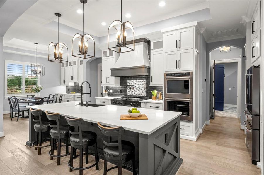 Pendant lighting above island tastefully designed to match groin entryway. Kitchen also features custom cabinetry with 42" wall cabinets and bonus display cabinets, soft-close doors and drawers