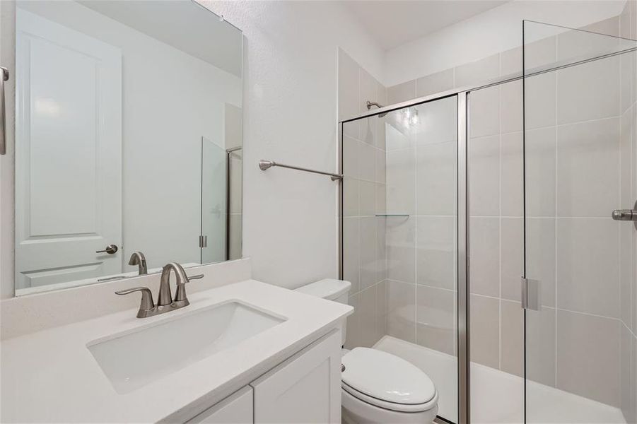 Bathroom featuring an enclosed shower, vanity, and toilet