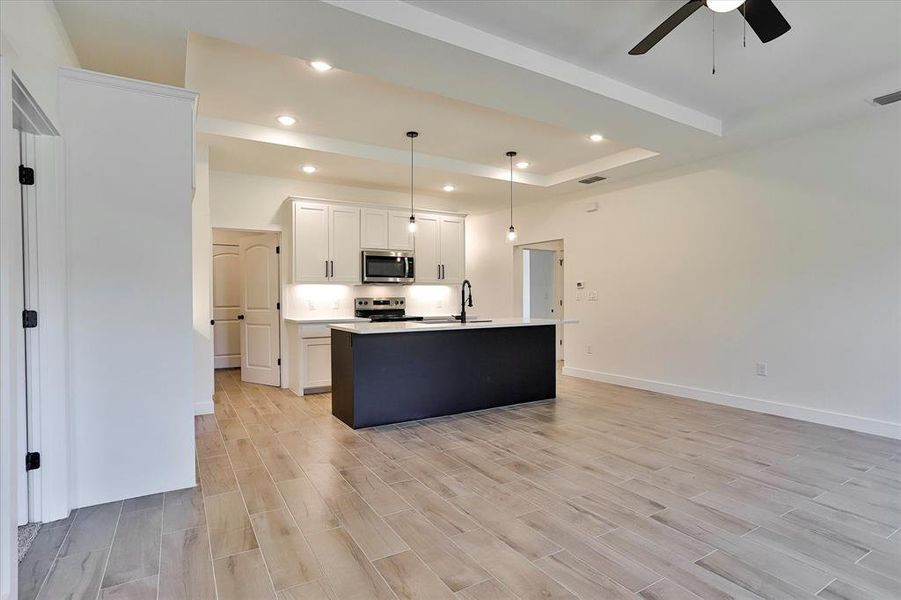 Kitchen featuring white cabinets, appliances with stainless steel finishes, light hardwood / wood-style floors, ceiling fan, and pendant lighting