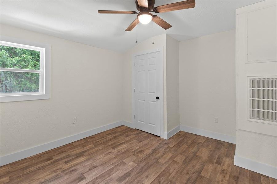 Empty room featuring dark hardwood / wood-style floors, vaulted ceiling, and ceiling fan