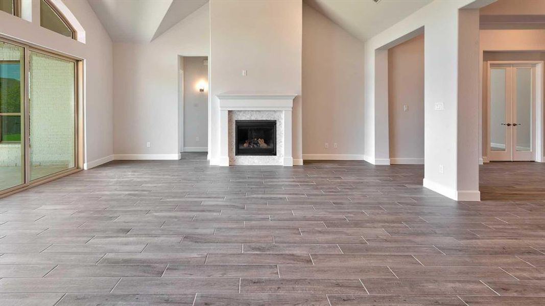 Unfurnished living room with vaulted ceiling, hardwood / wood-style floors, and a high end fireplace