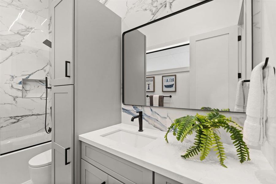 This first floor, en suite bathroom offers tile flooring, extended quartz countertop with ample storage and a tub/shower combo with glass door.