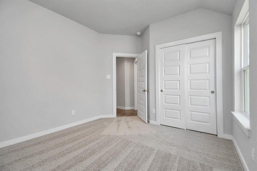 Generously sized secondary bedrooms featuring spacious closets, soft and inviting carpeting underfoot, large windows allowing plenty of natural light. Sample photo of completed home. As-built color and selections may vary.