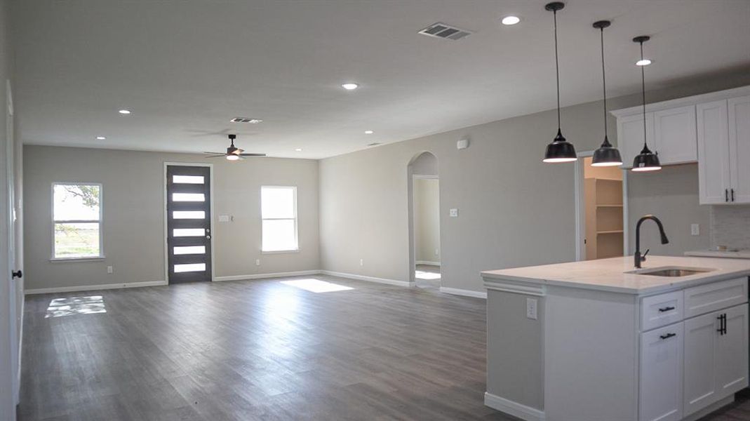 Kitchen with white cabinetry, dark wood-type flooring, sink, and a kitchen island with sink