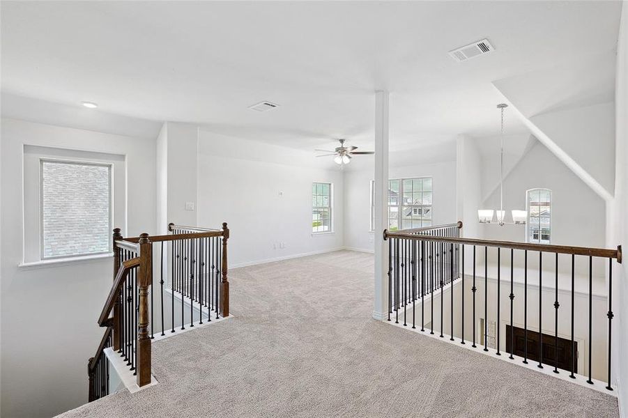 Corridor featuring an inviting chandelier and light colored carpet