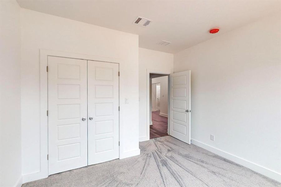 Unfurnished bedroom with light carpet and a closet