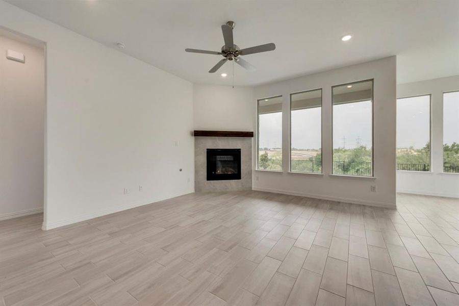 Unfurnished living room featuring a tiled fireplace and ceiling fan