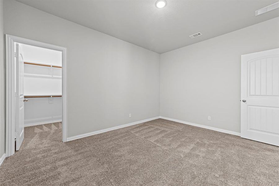 Unfurnished bedroom with a walk in closet, a closet, and carpet floors