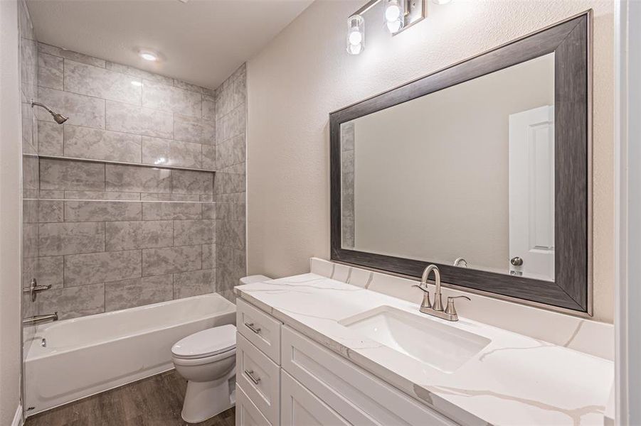Full bathroom featuring vanity, toilet, tiled shower / bath, and hardwood / wood-style flooring