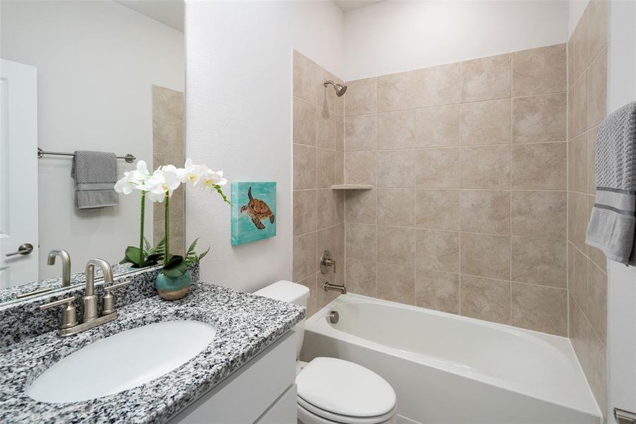 Full bathroom featuring vanity, toilet, and tiled shower / bath combo