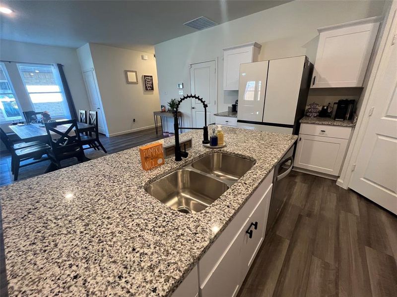 Kitchen with white cabinetry, dark hardwood / wood-style floors, light stone countertops, and sink