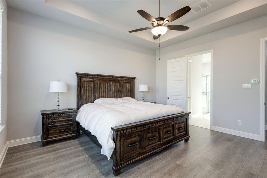 Bedroom featuring wood-type flooring, ensuite bath, and ceiling fan