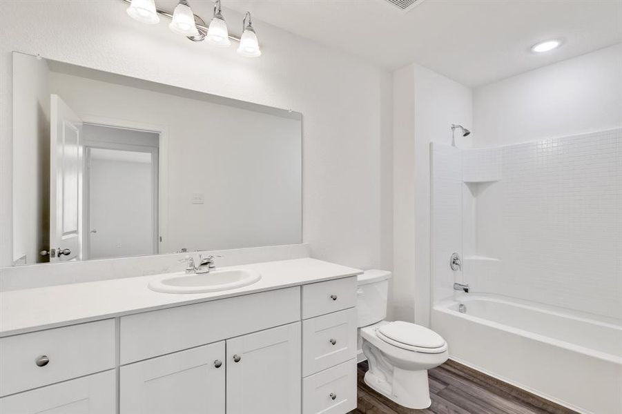 Full bathroom featuring wood-type flooring, shower / bath combination, vanity, and toilet