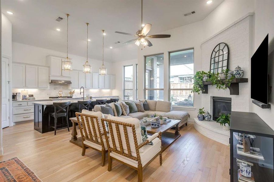 Living room featuring ceiling fan, a fireplace, sink, and light wood-type flooring