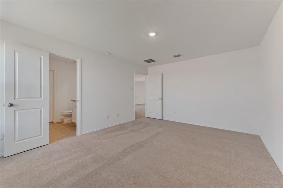 Unfurnished bedroom featuring light colored carpet and connected bathroom