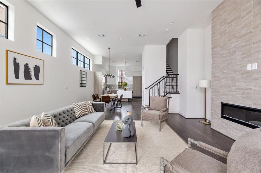 Indulge in the cozy elegance of this living room, where a linear fireplace wrapped in floor-to-ceiling porcelain takes center stage, framed by expansive windows.