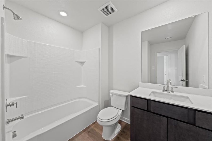 Full bathroom featuring vanity, toilet, wood-style flooring, and shower / washtub combination