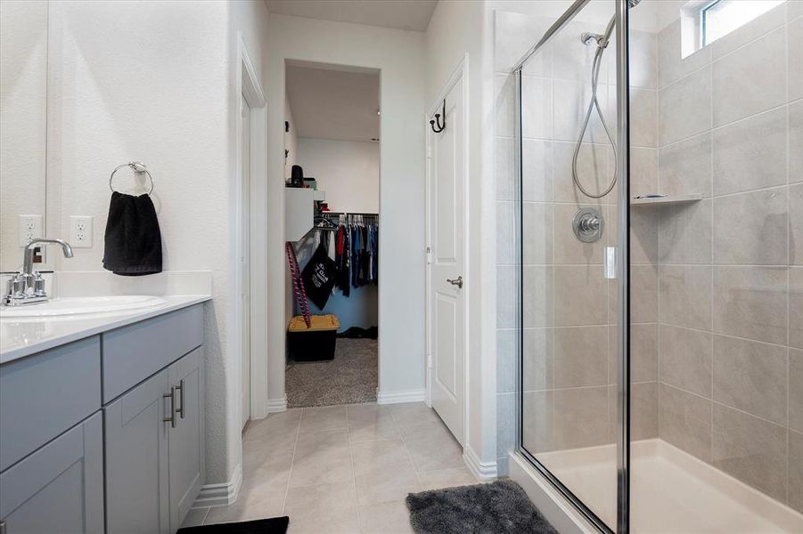 Bathroom featuring a shower with shower door, vanity, and tile patterned flooring