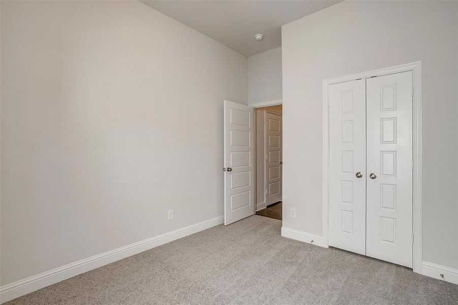 Unfurnished bedroom with light colored carpet and a closet