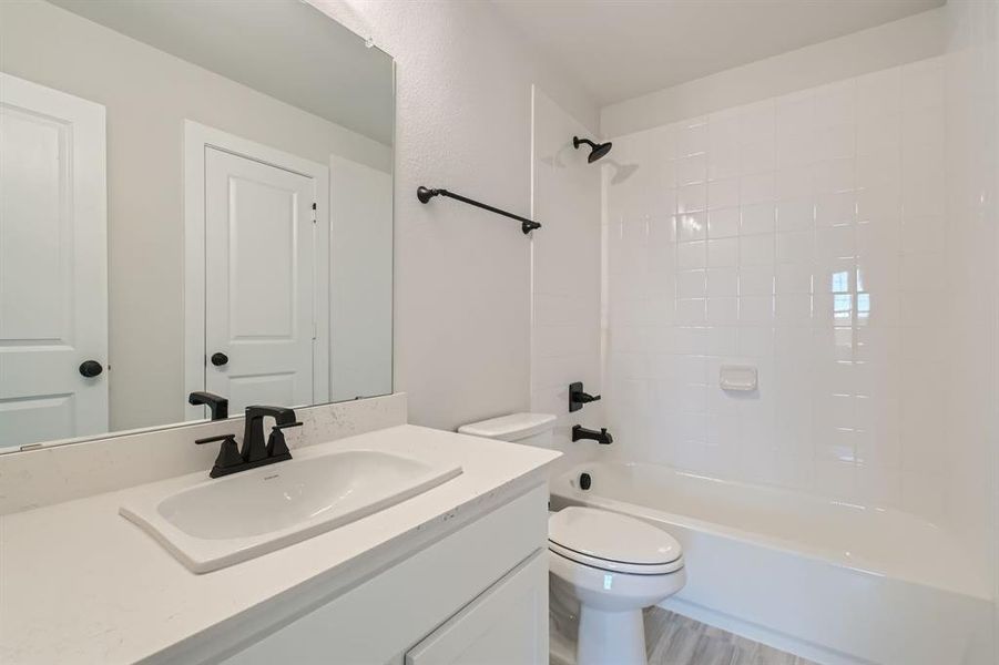 Full bathroom with vanity, tiled shower / bath combo, wood-type flooring, and toilet