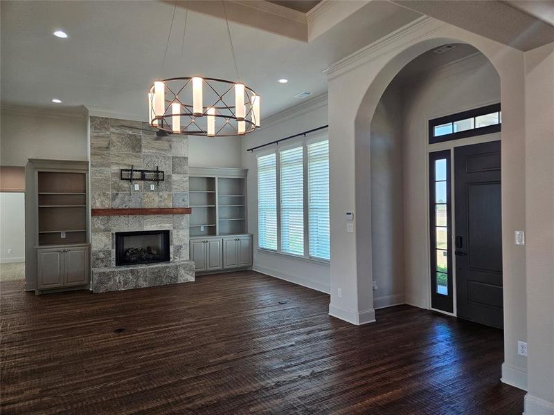 Foyer with an inviting chandelier, crown molding, a fireplace, and dark hardwood / wood-style flooring