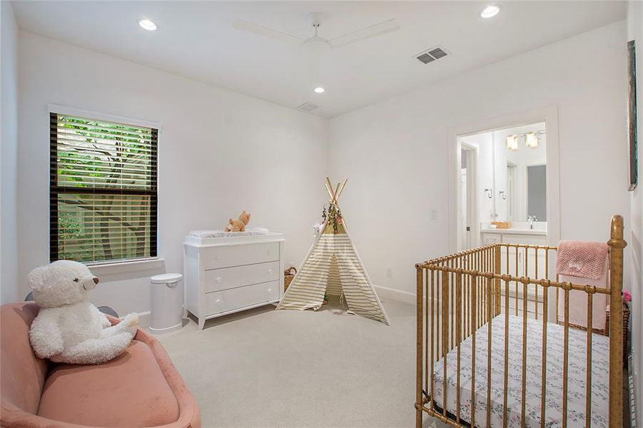Bedroom featuring a nursery area, ensuite bathroom, ceiling fan, and carpet floors